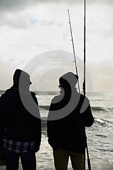 Having fun on a fishing trip. two young men fishing at the ocean in the early morning.