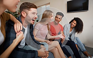 Having fun at home. Group of young happy multicultural people in casual wear enjoying time together while sitting on the