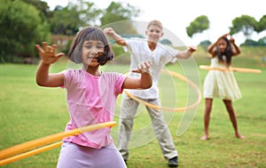 Having fun with hula-hoops. Three children playing with hula hoops outside.
