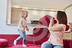 Having fun and jumping. Young mother with her little daughter in casual clothes together indoors at home