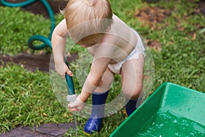 Having fun on my new adventure. A baby boy in his nappy and gumboots watering the garden.