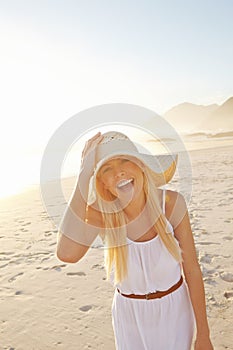 Having a fun time at the beach. Portrait of a gorgeous young woman wearing a white dress and sunhat on the beach.