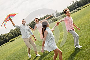 Having fun together. Happy and young family of four launcinging a kite in the field.