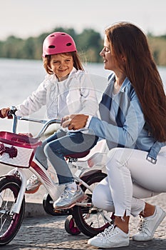 Having fun together. Mother with her young daughter is with bicycle outdoors together