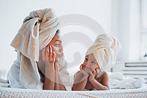 Having fun. Young mother with her daugher have beauty day indoors in white room