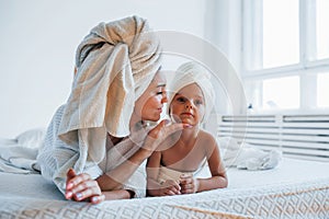 Having fun. Young mother with her daugher have beauty day indoors in white room