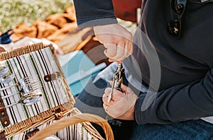 Having picnic. Closeup shot of man hands opening wine bottle