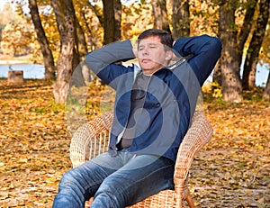 Having relaxed man is sitting in a wicker chair
