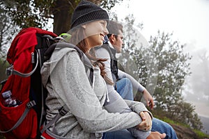 Having a rest in beautiful surroundings. a young couple sitting down for a rest while out hiking.