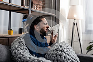 Unhappy ill man using a paper tissue