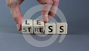 Having less stress or being stress-less. Businessman turns wooden cubes and changes the word `STRESS` to `LESS`. Beautiful gre