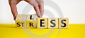 Having less stress or being stress-less. The word `STRESS` and `LESS` on wooden cubes. Male hand. Beautiful yellow table, whit