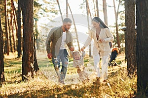 Having a walk. Happy family of father, mother and little daughter is in the forest