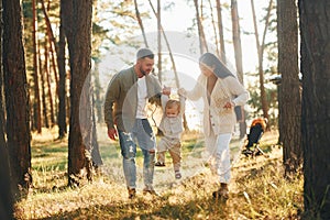 Having a walk. Happy family of father, mother and little daughter is in the forest