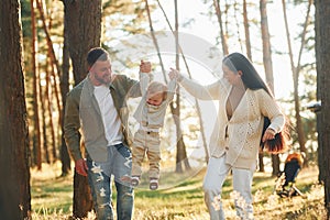 Having a walk. Happy family of father, mother and little daughter is in the forest