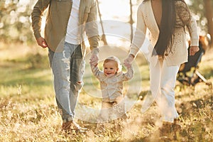 Having a walk. Happy family of father, mother and little daughter is in the forest