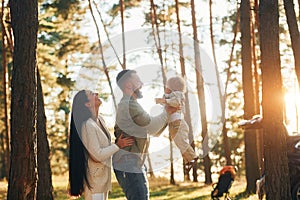 Having a walk. Happy family of father, mother and little daughter is in the forest