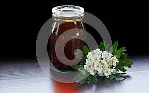 Haw decoction or extract from hawthorn berries with blossom of a tree, dark mood photo