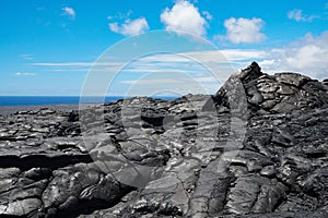 Hawaii hardened lava flow against a blue sky with the ocean in the distance