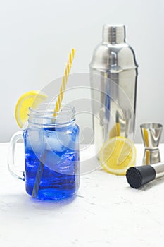 Hawaiian Blue Lagoon summer alcoholic cocktail with ice in glass jar. Bartender equipment shaker, jigger and muddler