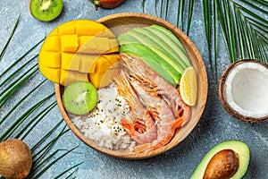 Hawaiian cuisine. Poke with shrimp, avocado, rice, mango, kiwi and coconut. Tropical food. Lunch on the beach. exotic dish. top