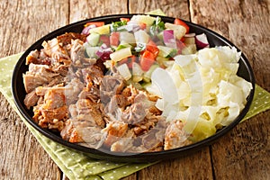 Hawaiian Kalua Pork with stewed cabbage and fresh salad close-up in a plate. horizontal