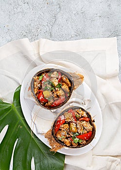 Hawaiian pinapple chicken in natural coconut shell plates on white background