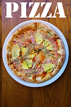 Hawaiian Pizza. A Ham and Pineapple Pizza on a white plate on a wooden table for lunch. Pizza is enjoyed world wide by hungry