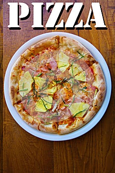 Hawaiian Pizza. A Ham and Pineapple Pizza on a white plate on a wooden table for lunch. Pizza is enjoyed world wide by hungry