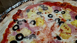 Hawaiian pizza with pineapple ham cheese and black olive close up shot home bake Italian fusion food