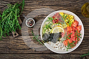 Hawaiian salmon fish poke bowl with rice, avocado, mango, tomato, sesame seeds and seaweeds.