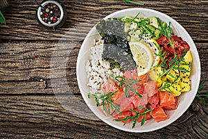 Hawaiian salmon fish poke bowl with rice, avocado, mango, tomato, sesame seeds and seaweeds.