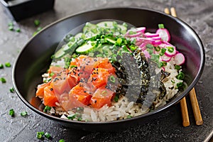 Hawaiian salmon fish poke bowl with rice, radish,cucumber, tomato, sesame seeds and seaweeds.