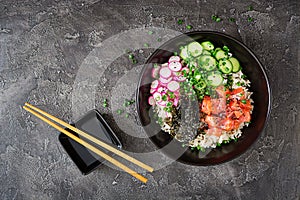 Hawaiian salmon fish poke bowl with rice, radish,cucumber, tomato, sesame seeds and seaweeds