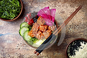 Hawaiian salmon poke bowl with seaweed, watermelon radish, cucumber, pineapple and sesame seeds. Copy space