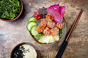 Hawaiian salmon poke bowl with seaweed, watermelon radish, cucumber, pineapple and sesame seeds. Copy space