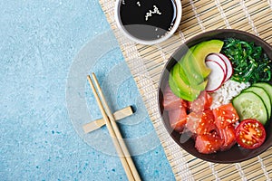 Hawaiian salmon poke salad with rice, chopsticks and soy sauce. Sushi bowl