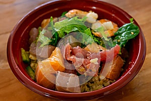 Hawaiian seafood poke bowl isolated on wooden table background