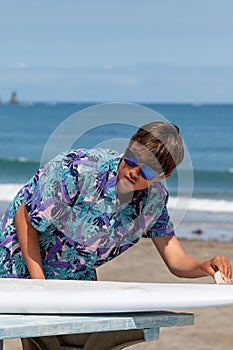 Hawaiian Shirt young Asian boy waxing a surfboard