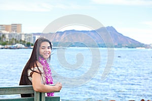 Hawaiian teen with lei sitting by ocean, Waikiki in background