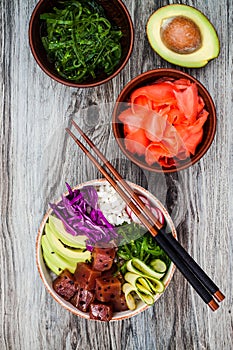 Hawaiian tuna poke bowl with seaweed, avocado, red cabbage, radishes and black sesame seeds.