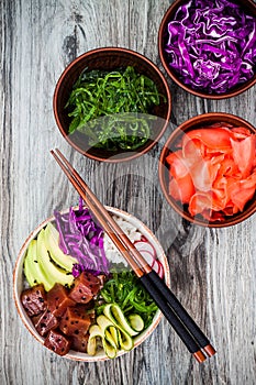 Hawaiian tuna poke bowl with seaweed, avocado, red cabbage, radishes and black sesame seeds.