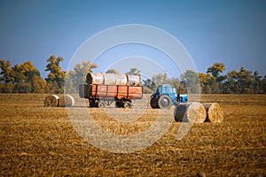 Hay bail harvesting in wonderful autumn farmers field landscape with hay stacks