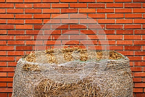 Hay bale against red brick wall on the ranch