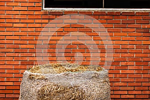 Hay bale against red brick wall on the ranch