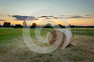 Hay bale in the meadow and the evening sky, Nowiny, Poland