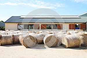 Hay bales are stacked in large stacks on an unknown riding centre