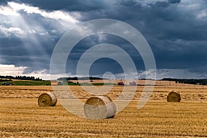 Hay bales under cloudy storm sky on harvested wheat field