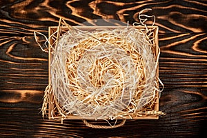 Hay in box on brown wooden pallet with decorative hay inside on a rustic table. top view, space for text