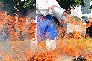 Hay fire. A man extinguishes a large fire in a meadow with a bucket of water. Farmer and fire
